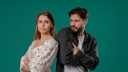Zwei Menschen stehen Rücken an Rücken; die gegenseitige Ablehnung ist ihren Gesichtern deutlich anzusehen.