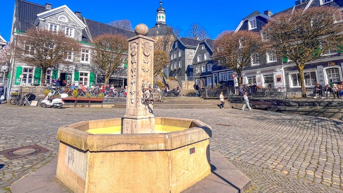 Gräfrather Marktplatz mit Brunnen und Bäumen