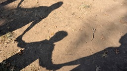 Schatten von Kindern, die sich an der Hand halten, auf dem Boden