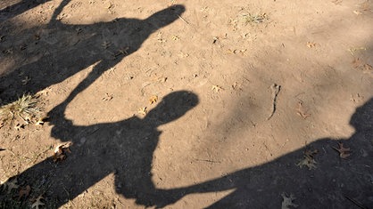 Schatten von Kindern, die sich an der Hand halten, auf dem Boden
