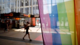 Vor dem Infoschalter der Deutschen Bahn im Kölner Hauptbahnhof stehen Regenbogenflaggen. 