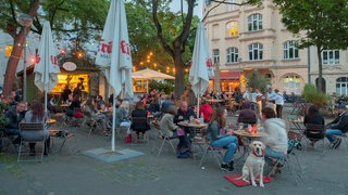 Menschen sitzen in einer Außengastronomie in Köln Nippes.