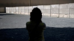 Silhouette einer Person vor der Gedenkstätte Berliner Mauer.