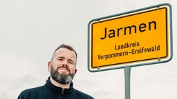 Monchi neben dem Ortsschild von Jarmen