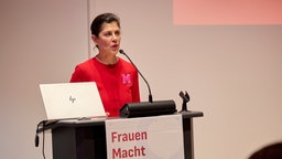 Murielle Guéguen steht an einem Podium und spricht in ein Mikrofon.