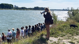 Menschen am Rhein und eine Frau mit Megafon