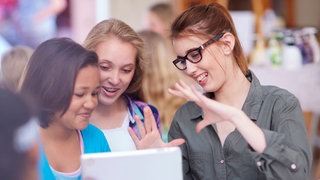 Eine junge Frau erklärt zwei Schülerinnen
