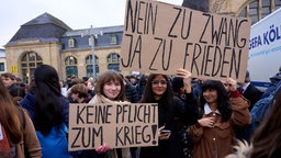 Schülerinnen und Schüler halten bei einem Schulstreik gegen die Wiedereinführung der Wehrpflicht Plakate hoch