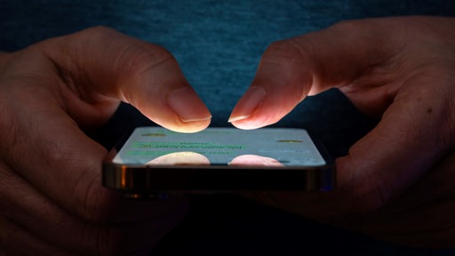 Nahaufnahme eines Smartphones, das von zwei Händen gehalten wird.