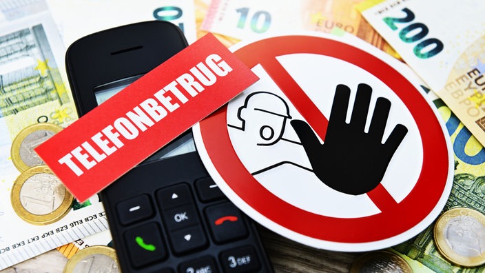 Nahaufnahme eines Telefons und von Bargeld mit einem Warnhinweis vor Telefonbetrug.