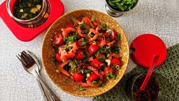 Tomatensalat in einer Schüssel mit einem silbernen Löffel.