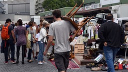 Ein Mann trägt einen alten Stuhl über einen Flohmarkt in Düsseldorf.