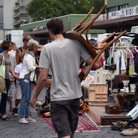 Ein Mann trägt einen alten Stuhl über einen Flohmarkt in Düsseldorf.