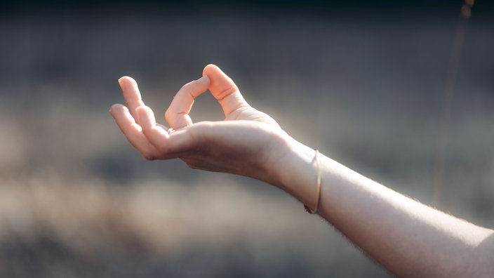 Zeigefinger und Daumen formen einen Kreis beim Meditieren