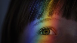 Brechung des Lichts in Regenbogenfarben auf dem Auge eines Kindes