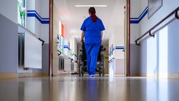 Krankenpflegerin schiebt einen Rollstuhl 