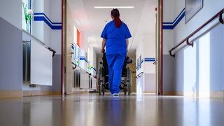 Krankenpflegerin schiebt einen Rollstuhl 
