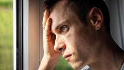 Ein Mann steht verzweifelt an einem Fenster