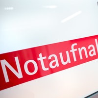 Ein Krankenpfleger steht in einem Krankenhaus neben einer Glastür mit der Aufschrift «Notaufnahme»