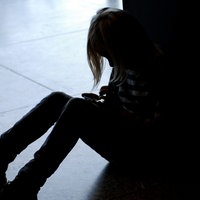 Ein kleines Mädchen sitzt allein auf dem Fußboden und hat den Kopf gesenkt