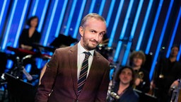 Moderator Jan Böhmermann steht in seinem Studio und lacht