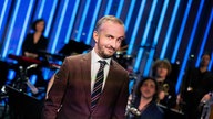 Moderator Jan Böhmermann steht in seinem Studio und lacht
