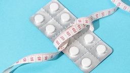 Eine Blisterverpackung mit Abnehmtabletten, umgeben von einem Maßband.