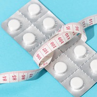 Eine Blisterverpackung mit Abnehmtabletten, umgeben von einem Maßband.
