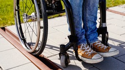 Die Füße einer jungen Frau im Rollstuhl