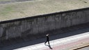 Eine Joggerin läuft vor einem der wenigen noch erhaltenen Abschnitte der Berliner Mauer.