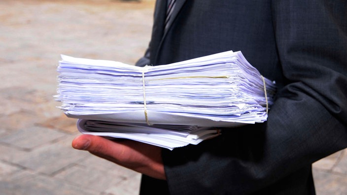 Symbolbild Bürokratie: Eiin Mann trägt einen Stapel Papier