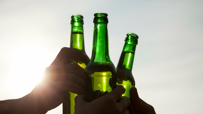 Symbolbild Alkoholkonsum: Freunde stoßen mit Bierflaschen an
