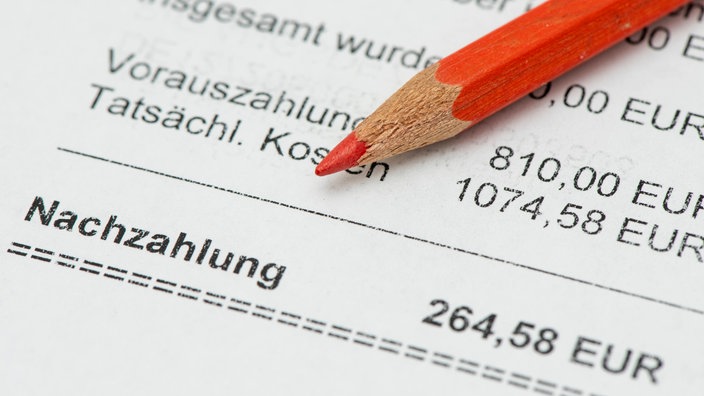 Ein roter Stift liegt auf einer Abrechnung mit einem Nachzahlungsbetrag