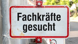 Ein rechteckiges Straßenschild in Weiß mit rotem Rand und der Aufschrift „Fachkräfte gesucht“.