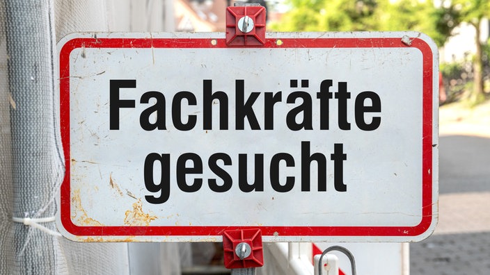 Ein rechteckiges Straßenschild in Weiß mit rotem Rand und der Aufschrift „Fachkräfte gesucht“.