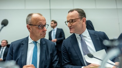 Jens Spahn spricht mit dem erstaunten Bundeskanzler Friedrich Merz vor Beginn einer Fraktionssitzung im Bundestag.