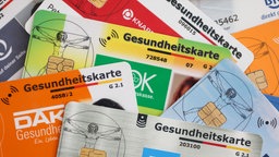 Nahaufnahme mehrerer Gesundheitskarten verschiedener Krankenkassen.