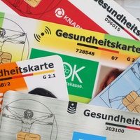 Nahaufnahme mehrerer Gesundheitskarten verschiedener Krankenkassen.