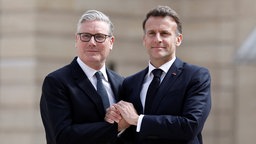 Emmanuel Macron und Keir Starmer halten ihre Hände am 17. April 2026