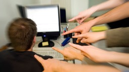 Symbolbild Mobbing am Arbeitsplatz: Mehrere Zeigefinger zeigen auf einen Mann.