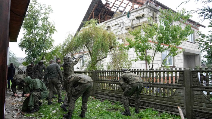 In Wyryki bei Lublin (Polen) räumen Beamte der Territorialen Verteidigung Trümmer vom zerstörten Dach eines Hauses auf