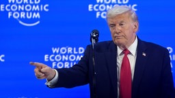 Trump steht auf einer Bühne beim Weltwirtschaftsforum in Davos und zeigt mit forderndem Zeigefinger auf das Publikum.