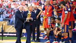Trump und Infantino tragen den WM-Pokal gemeinsam zur Siegerehrung des WM-Finales.