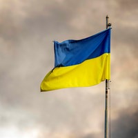 Die ukrainische Flagge ist vor dem Rauch eines Feuers zu sehen, nach Angriffen auf die Ukraine über Kiew.
