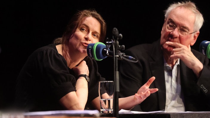 Ella Carina Werner spricht in ein WDR Mikro im Hintergrund Jörg Maurer