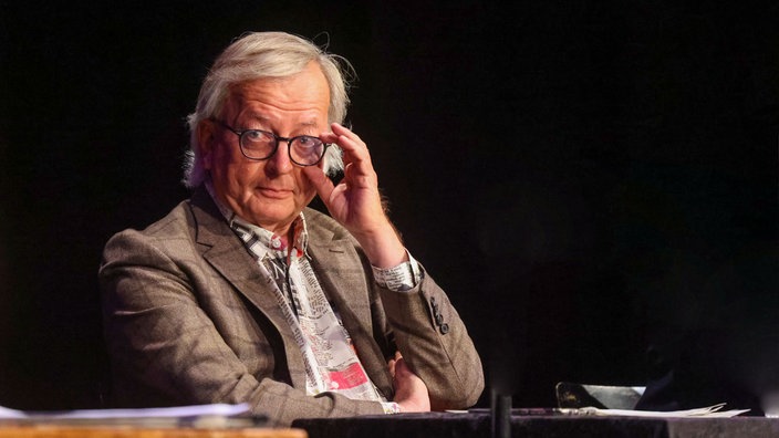 Hans Zippert fasst sich an Brille auf der Bühne vom Pantheon in Bonn