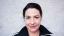 Portrait der Kabarettistin Eva Eiselt vor hellem Hintergrund, sie lächelt in die Kamera