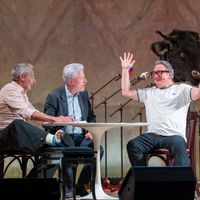 Das Kabarett-Trio "Wir Staatskünstler" sitzt beim Salzburger Stier 2026 an einem Tisch auf der Bühne