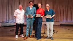  Bodo Wartke, Sonja Pikart und Markus Schönholzer posieren mit ihren Trophäen beim Salzburger Stier 2026, daneben Moderator Robert Palfrader