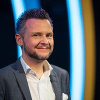 Moderator Tobias Mann steht während der Verleihung des 50. Deutschen Kleinkunstpreises 2022 im Frankfurter Hof auf der Bühne und lächelt in die Kamera. 
